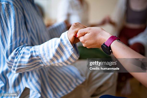 patienten, die sich während der psychotherapiesitzung an den händen halten, um unterstützung und psychische gesundheit zu erhalten - laubsäge stock-fotos und bilder
