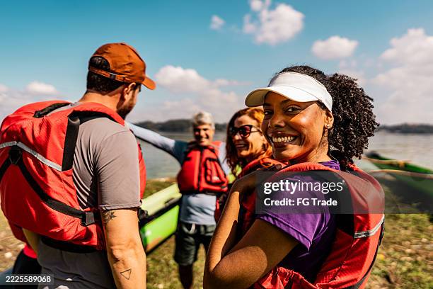 portrait of a mid adult woman with her friends in a lake before aquatic sport - white water rafting stock pictures, royalty-free photos & images