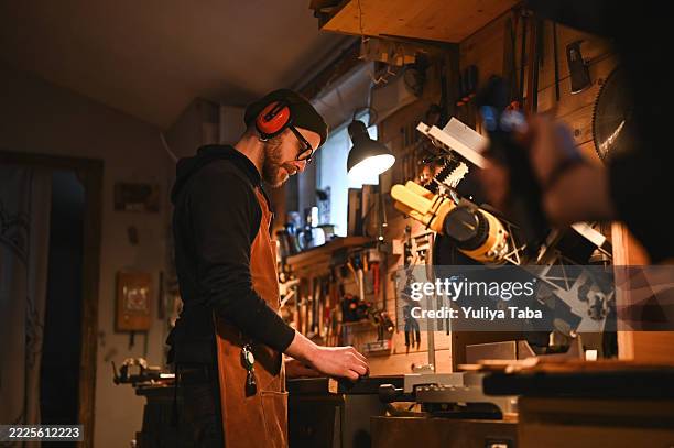 charpentier travaillant avec une scie électrique en atelier - établi photos et images de collection
