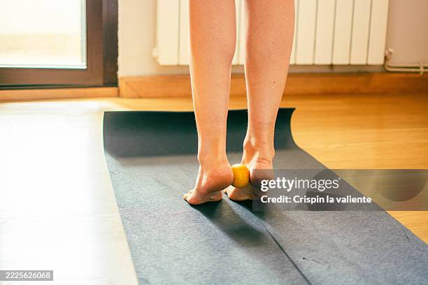 woman massaging feet with tennis ball on yoga mat - plantar fasciitis stock pictures, royalty-free photos & images