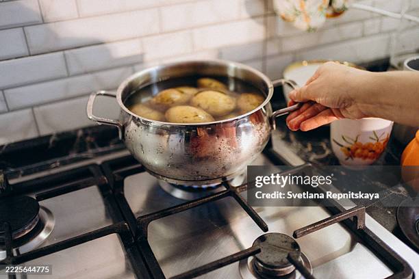chef boiling potatoes in a saucepan on a gas stove - hervir fotografías e imágenes de stock