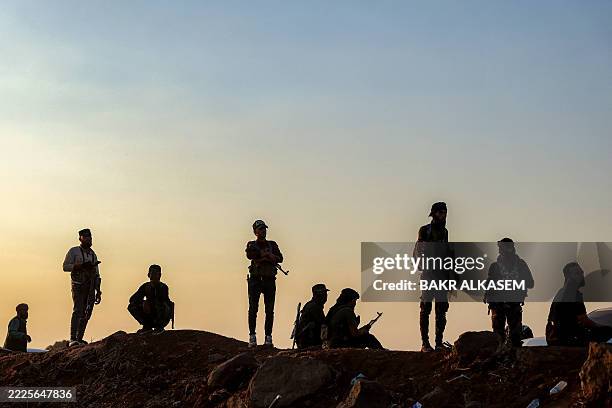 Syrian security forces stand by as a United Nations convoy evacuating families from Sweida moves through the buffer zone in Busra al-Harir in Syria's...
