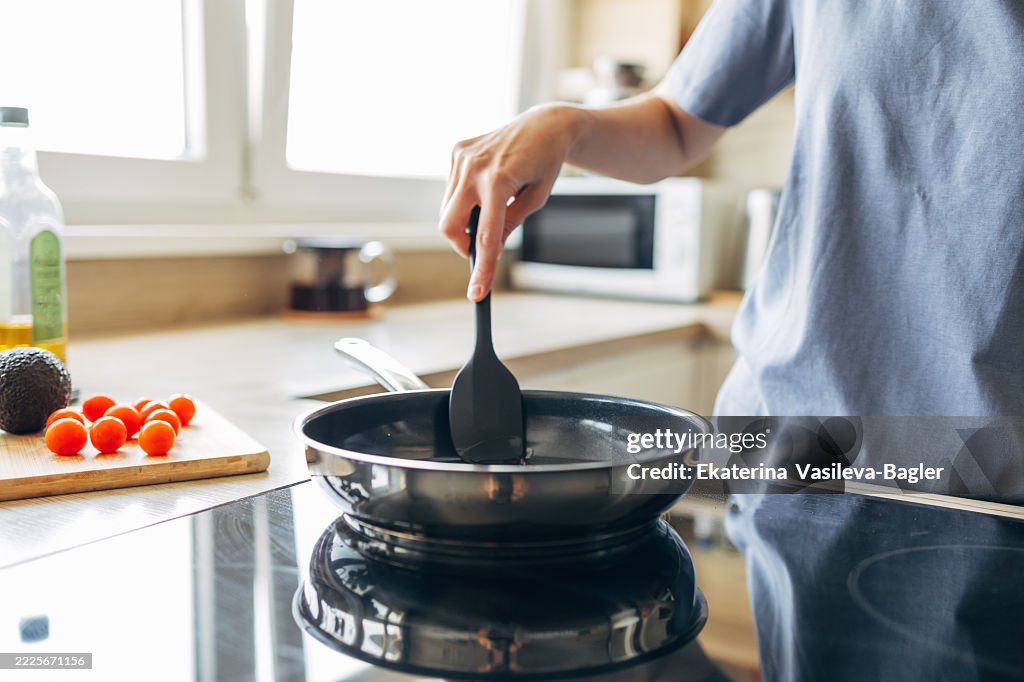 Chef using spatula while cooking in frying pan on induction stove