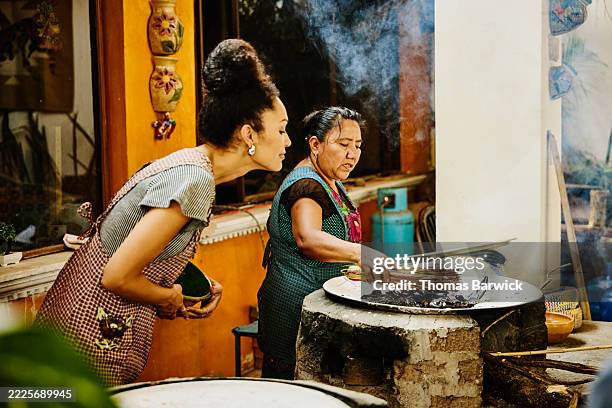 medium shot oaxacan cook showing student to roast chilis on grill - medium shot stock pictures, royalty-free photos & images