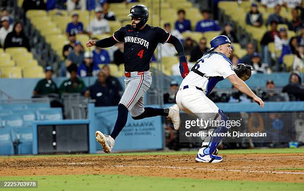 Carlos Correa of the Minnesota Twins scores a run on a double by teammate Ty France against catcher Will Smith of the Los Angeles Dodgers during the...