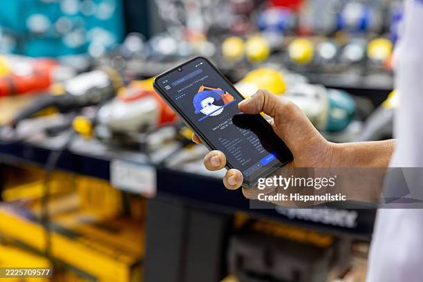 close-up on a man at a hardware store holding a cell phone with details of a tool - power tool stock pictures, royalty-free photos & images