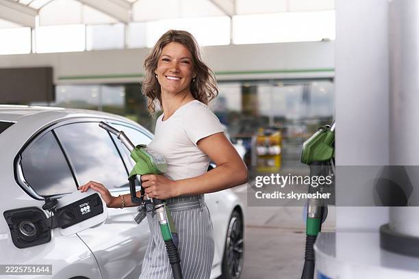 carefree woman about to refuel her car tank at gas station. - refueling stock pictures, royalty-free photos & images