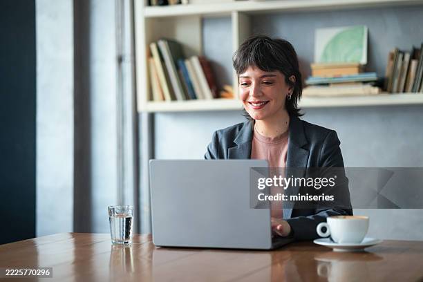 smiling businesswoman working on laptop at modern office desk - tidy room stock pictures, royalty-free photos & images