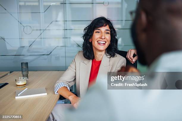 smiling woman in business meeting engaging with colleague at office table - business meeting stockfoto's en -beelden