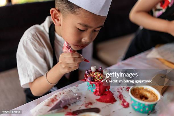 little boy decorating a cupcake - cupcake stock pictures, royalty-free photos & images