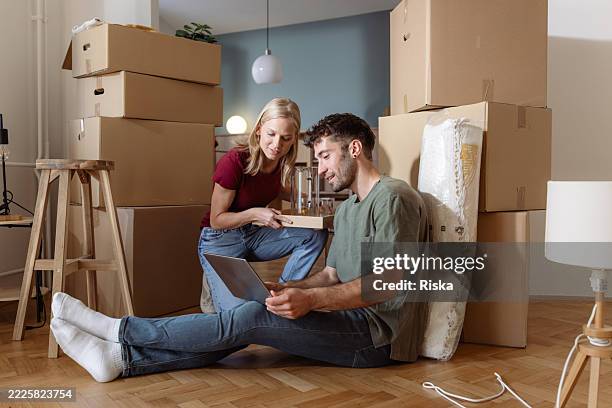 junges paar, das sein neues zuhause während eines umzugsprozesses organisiert - umzug stock-fotos und bilder