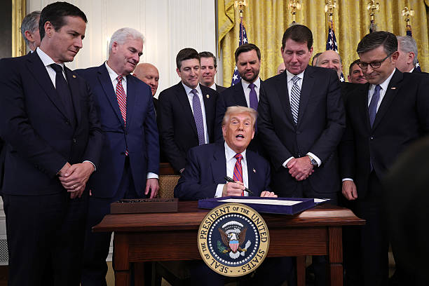 President Donald Trump, surrounded by lawmakers signs, the “GENIUS Act” into law during a ceremony in the East Room of the White House July 18, 2025...