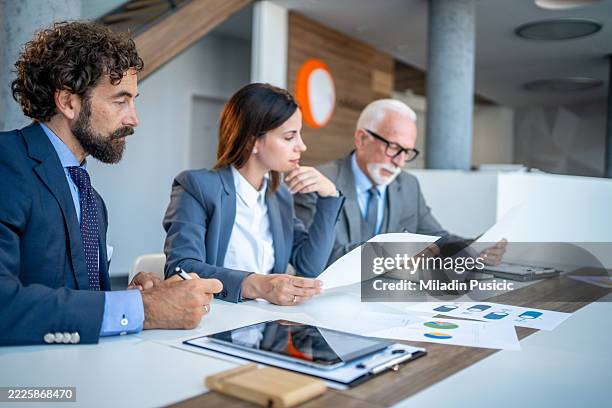 business people reading documents during a corporate meeting - financial report stock pictures, royalty-free photos & images
