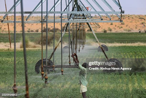 Herder checks on the operation of a center-pivot irrigation system in an alfalfa field at the Livestock Demonstration Center in Idini village,...