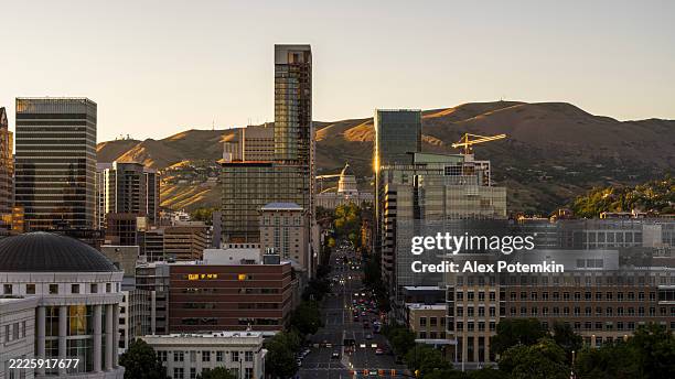 der sonnenuntergang erleuchtet hochhäuser. die state street erstreckt sich durch den stadtteil liberty-wells in salt lake city, utah, und führt zum state capitol. - salt lake city and county verwaltungsgebäude stock-fotos und bilder