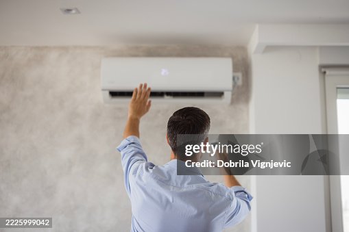 Technician checking air conditioning unit using remote control Technician checking air conditioning unit using remote control