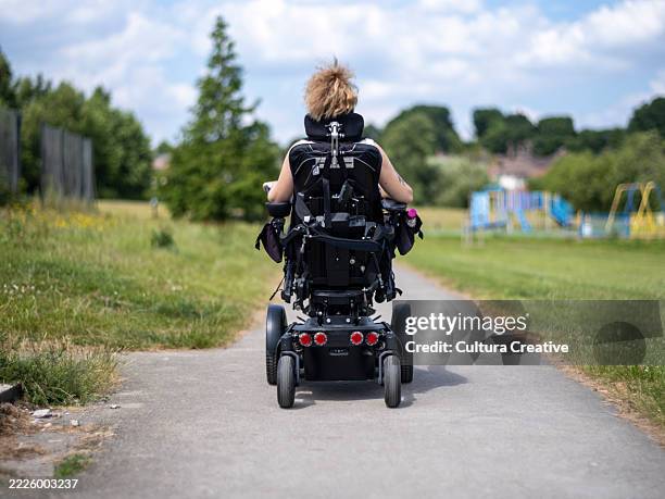 woman in electric wheelchair going on walk - motorized wheelchair stock pictures, royalty-free photos & images