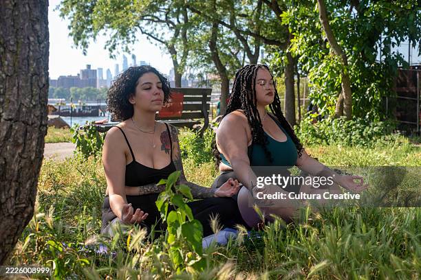 two women meditating in park - aum sign stock pictures, royalty-free photos & images