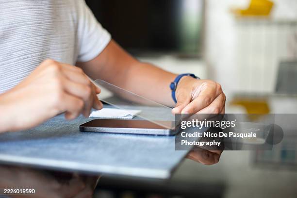man applying new screen protector to smartphone after glass replacement - screen replacement stock pictures, royalty-free photos & images