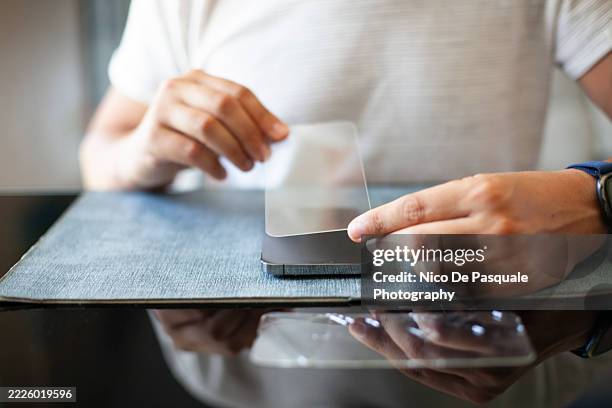 man applying new screen protector to smartphone after glass replacement - screen replacement stock pictures, royalty-free photos & images
