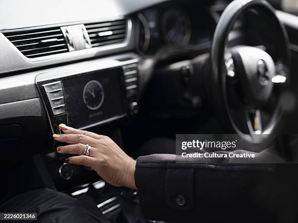 woman using dashboard buttons in car - hands steering wheel stock pictures, royalty-free photos & images