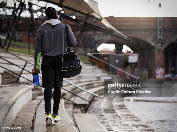 rear view of athletic man with gym bag walking outdoors - sporttasche stock-fotos und bilder