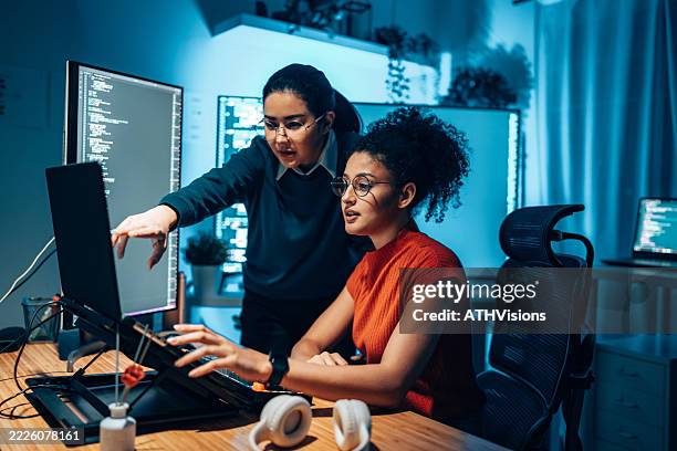 diversity female software engineers collaborating on code in modern tech office at night - computer lock stock pictures, royalty-free photos & images
