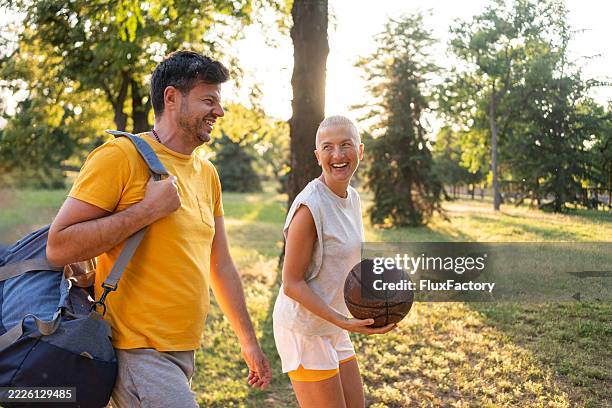 pareja de mediana edad disfrutando de actividades de baloncesto en el parque al atardecer - pareja de mediana edad fotografías e imágenes de stock