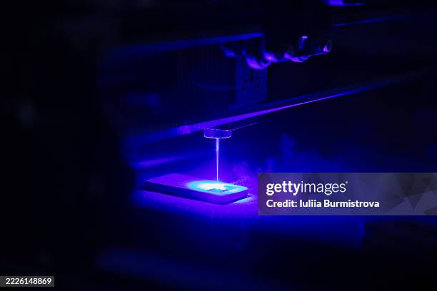blue laser engraving process on dark background with detailed close-up view - holz laser stock-fotos und bilder