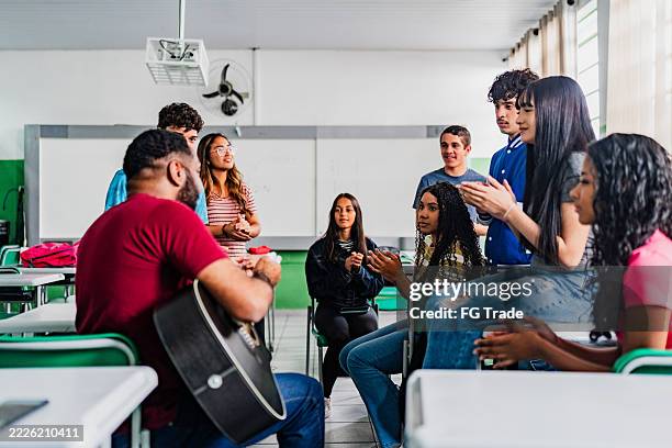 musiklehrer gibt gymnasiasten im klassenzimmer gitarrenunterricht - musikalische begleitung stock-fotos und bilder