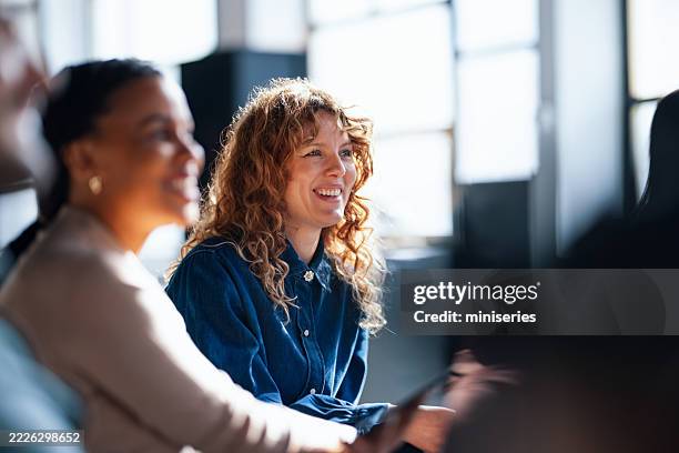 colleghi sorridenti che interagiscono durante una riunione informale in ufficio in uno spazio illuminato - sovraesposizione effetti fotografici foto e immagini stock