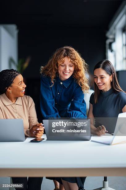 three women collaborating on a project in a modern office setting - staff meeting stock pictures, royalty-free photos & images