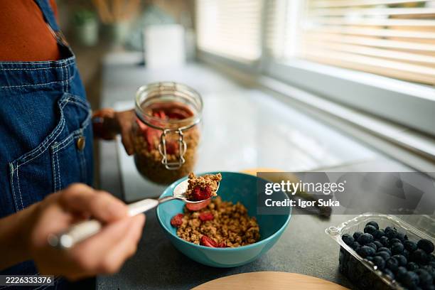 mujer preparando un tazón de granola con fresas para el desayuno - fibra fotografías e imágenes de stock