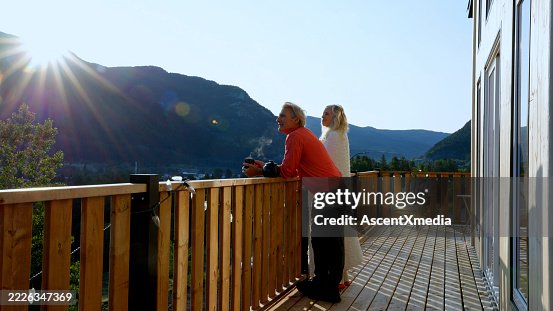 Mature couple enjoy hot tea on cabin deck at sunrise Mature couple enjoy hot tea on cabin deck at sunrise