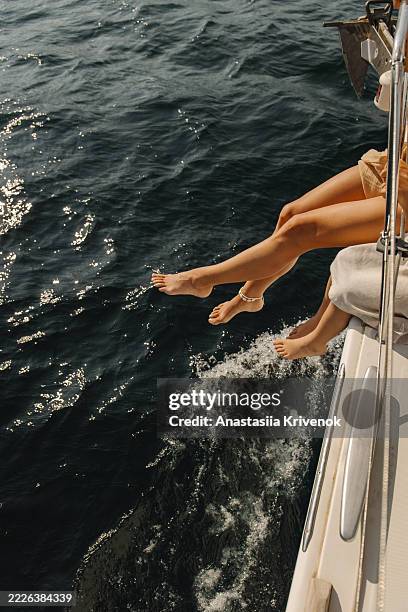 relaxing on a yacht with legs dangling over sparkling ocean water - barco de vela fotografías e imágenes de stock