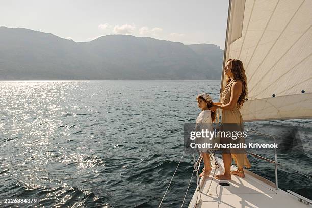 mother and daughter enjoying scenic sailing adventure on the ocean - richesse photos et images de collection