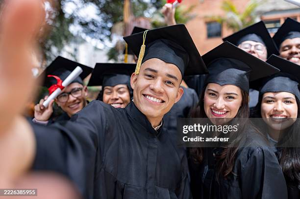 happy group of graduates taking a selfie on their graduation day - alumni stock pictures, royalty-free photos & images