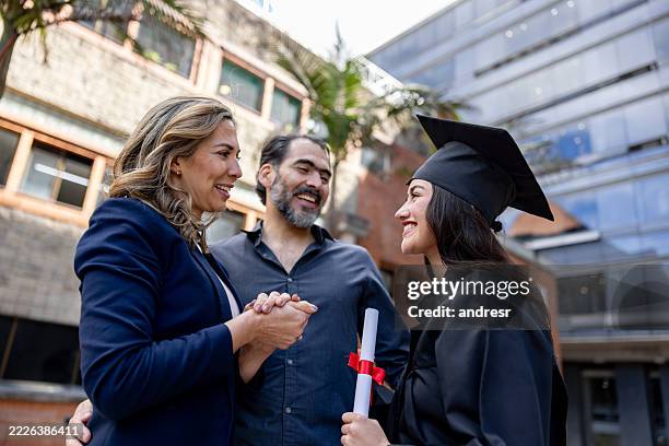 genitori felici che si congratulano con la figlia per la sua laurea - laurea foto e immagini stock