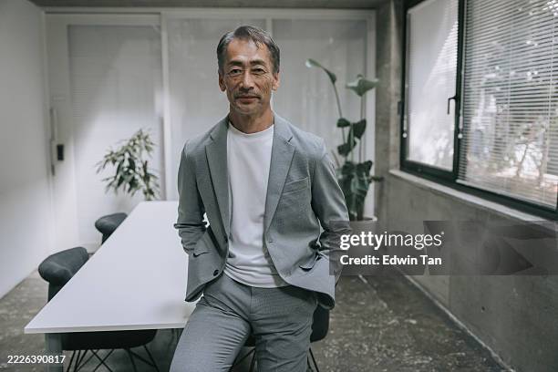 confident senior businessman standing in modern office space - founder stock pictures, royalty-free photos & images