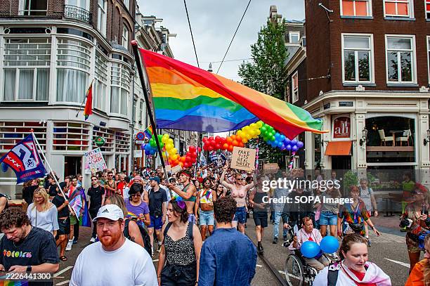 Man is seen carrying a big rainbow flag during the rally. The annual Pride Parade for the global rainbow community took place in Amsterdam. People...