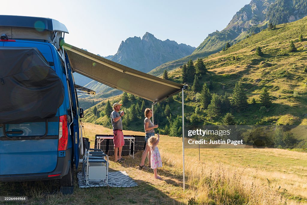 A family take in the view of the French Pyrenees mountains from their campervan on a sunny summer's morning