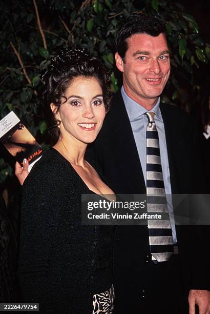 American actress Jami Gertz, wearing a black cardigan over a black scoop-neck top, and her husband, American businessman Tony Ressler, who wears a...