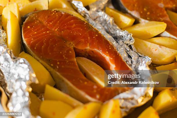 raw salmon steaks with seasoned potatoes in foil wrapping - frozen fish fillets stockfoto's en -beelden