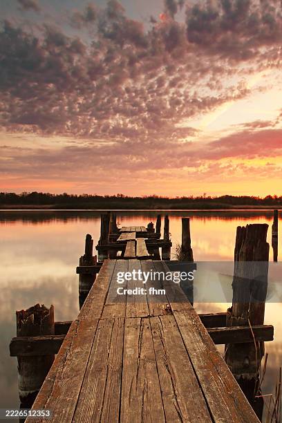old damaged wooden jetty at a lake at sunset - ponton photos et images de collection
