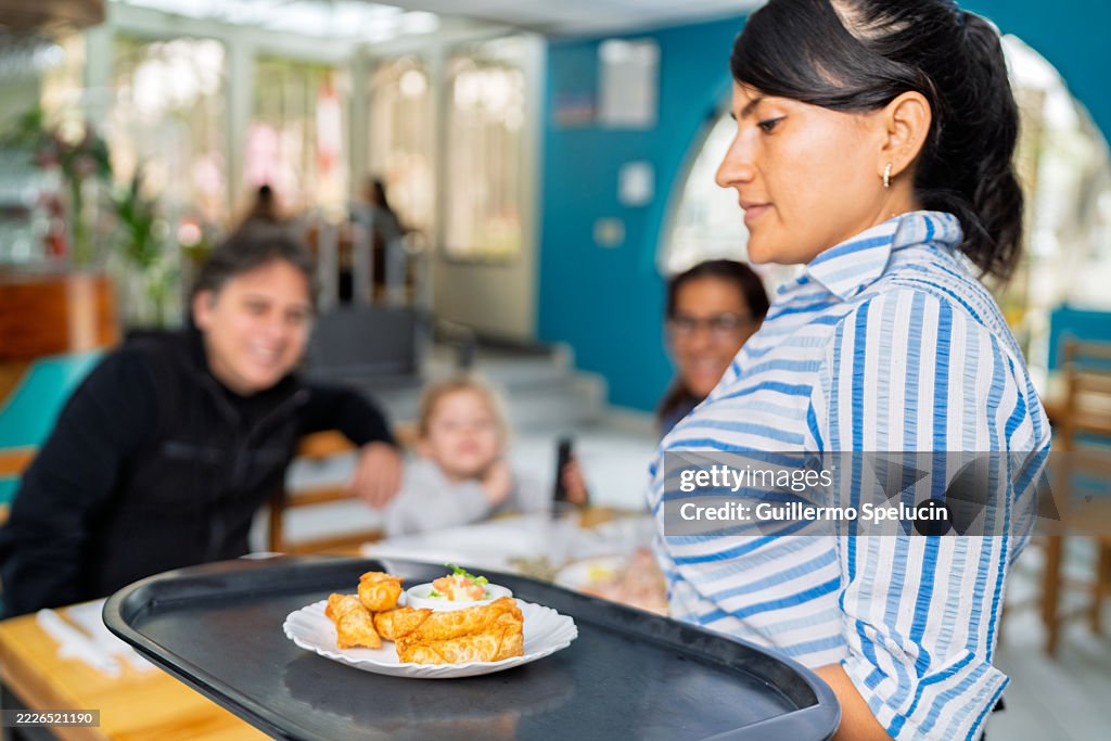 Waitress carrying tray with fried seafood at restaurant