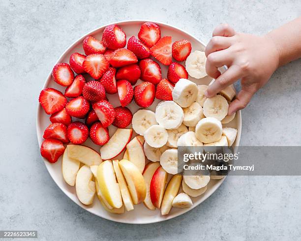 fruit snack plate with a child's hand - strawberry banana stock pictures, royalty-free photos & images