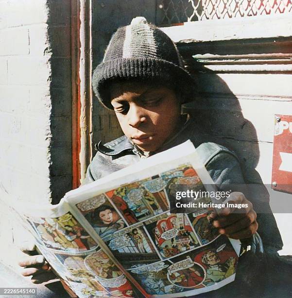 Washington, D.C. Negro youth reading a funny paper on a door step in the Southwest section. . Creator: Gordon Parks.