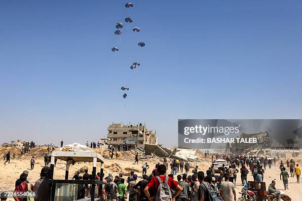 People gather as a C-130 Hercules military transport aircraft drops humanitarian aid on the northern Gaza Strip on July 27, 2025. Two Jordanian and...