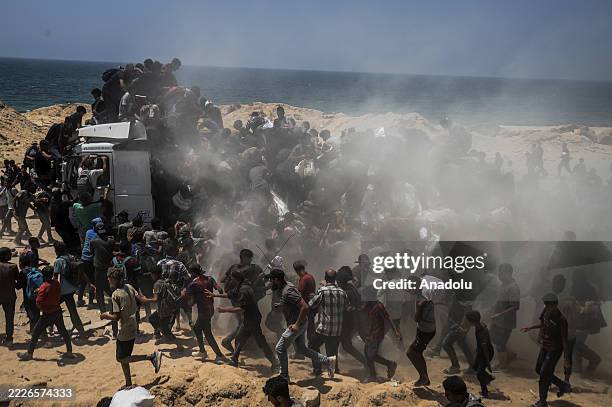 Palestinians walk for kilometers after receiving flour aid distributed from trucks that entered the Zikim area, a kibbutz in southern Israel, amid...
