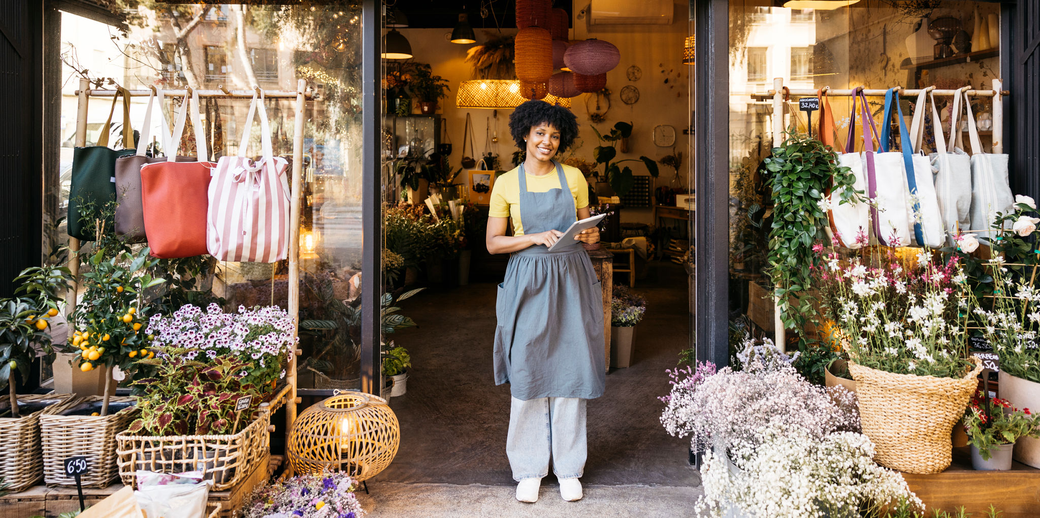 Florist owner smiling and using digital tablet in front of flower shop Florist owner smiling and using digital tablet in front of flower shop
